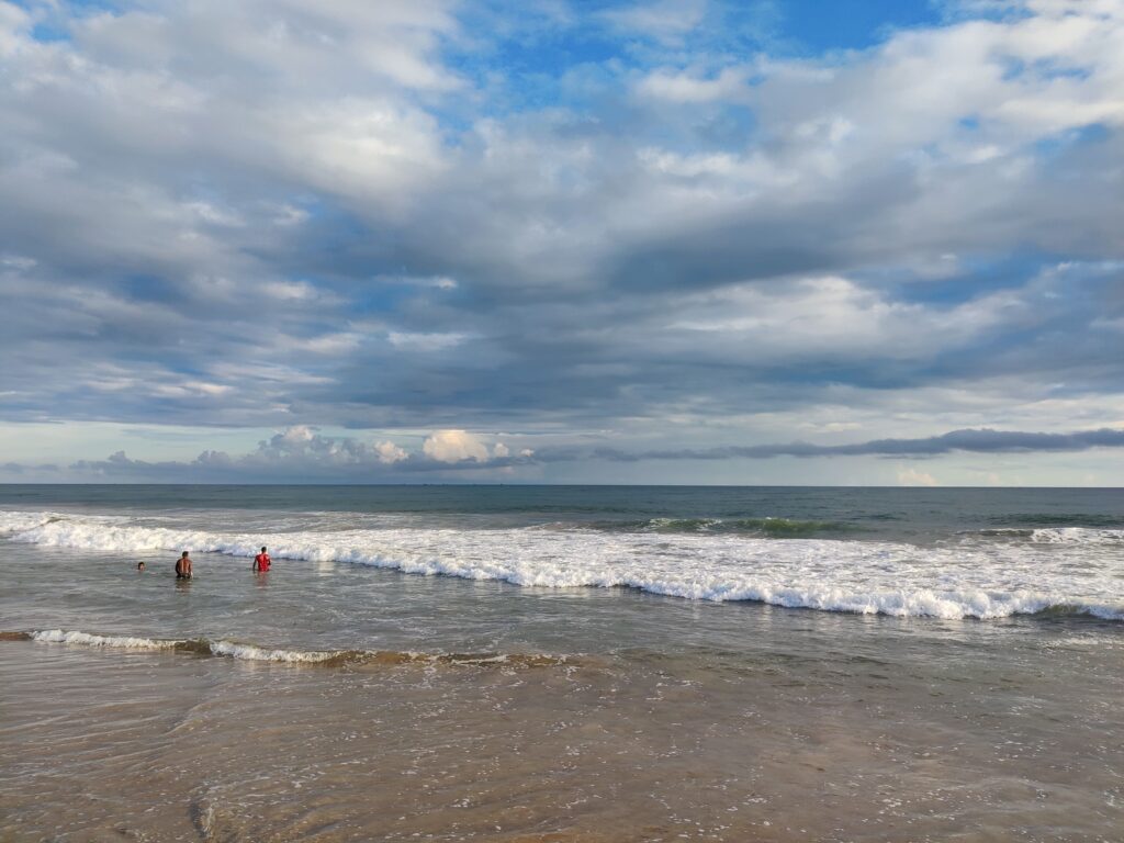 Evening view of  chandrabhaga Beach in Odisha with sandy dunes, ocean waves, and visitors walking along the shoreline”